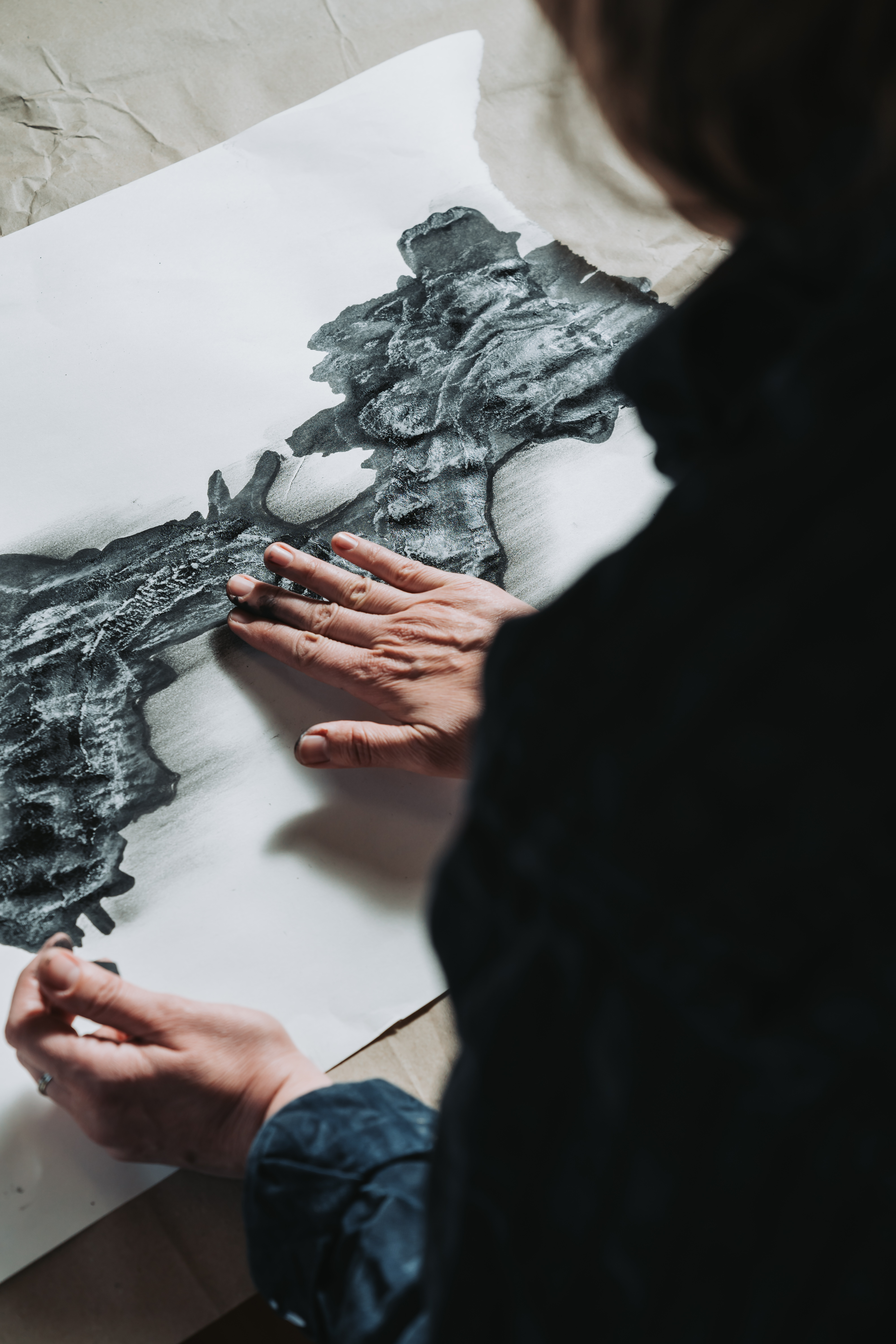 Hands working on charcoal drawing